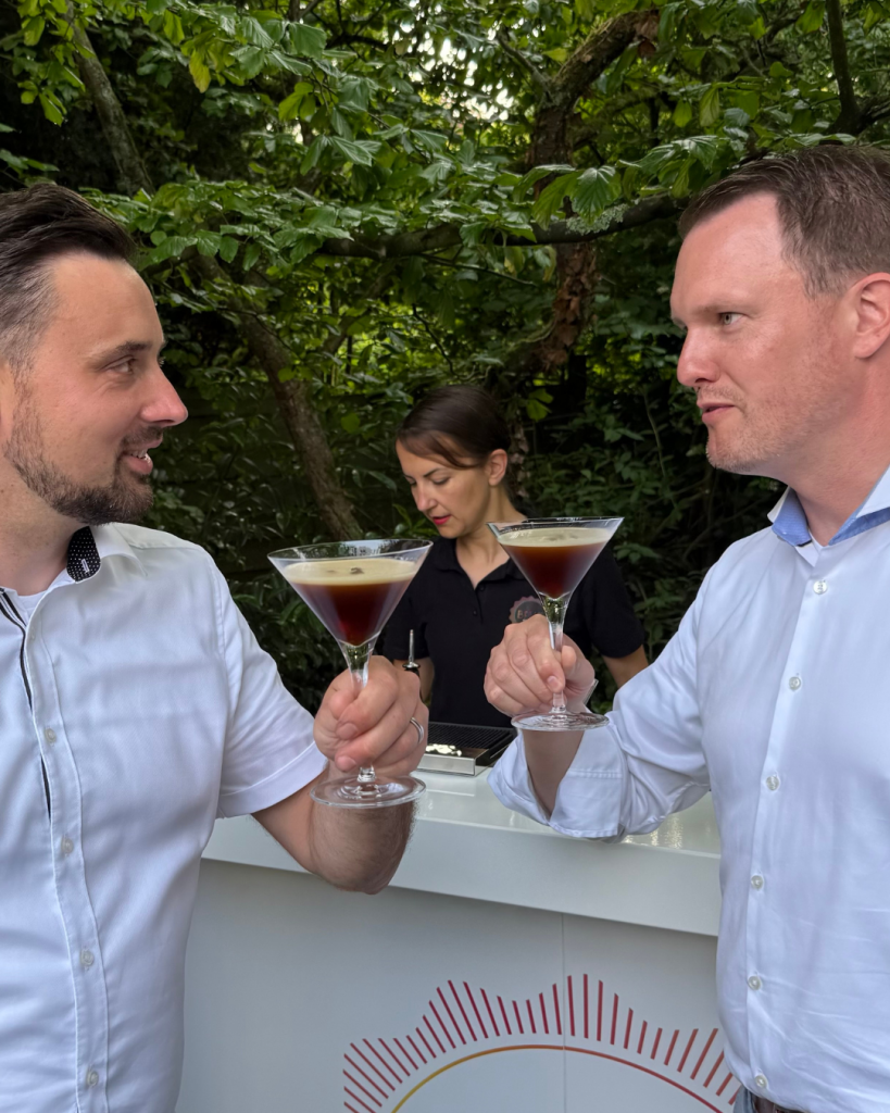 Zwei Gäste stoßen mit frisch vom Cocktail Catering der Break Pop-Up Bar zubereiteten Espresso Martinis an.