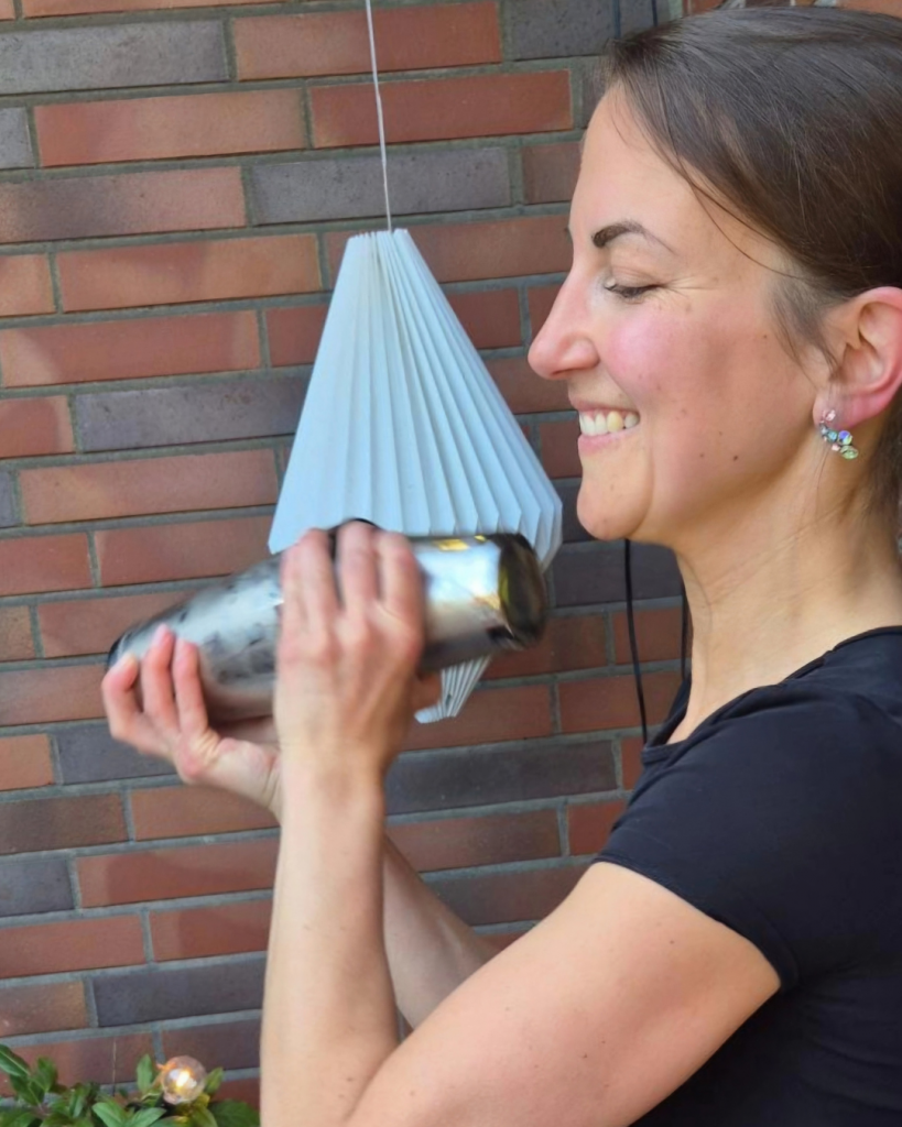 Barkeeperin schüttelt lächelnd den Cocktailshaker bei einer Veranstaltung vom Cocktail Catering der Break Pop-Up Bar.